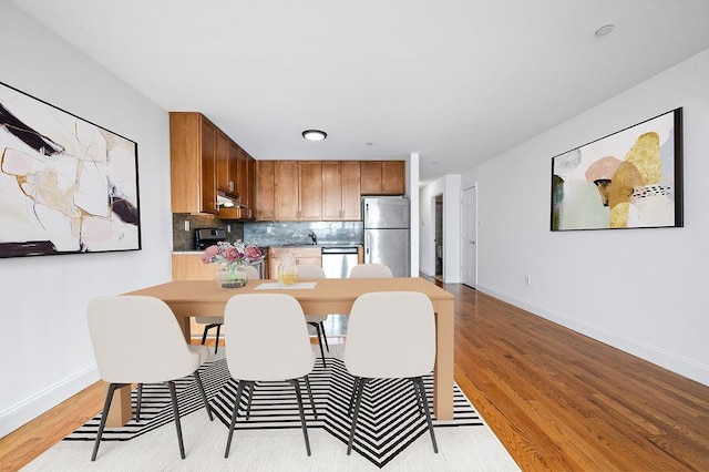 kitchen with light wood-type flooring, stainless steel appliances, and tasteful backsplash