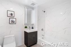 full bathroom featuring washtub / shower combination, vanity, and toilet