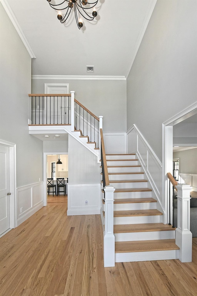 stairway with a notable chandelier, hardwood / wood-style flooring, and ornamental molding