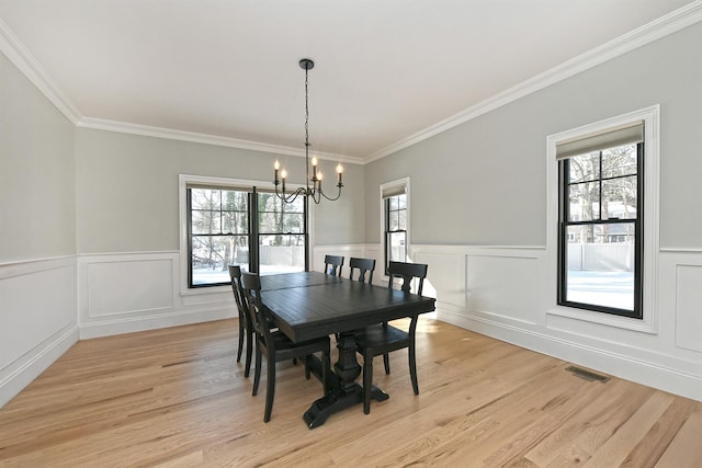 dining room with crown molding, light hardwood / wood-style flooring, and a notable chandelier