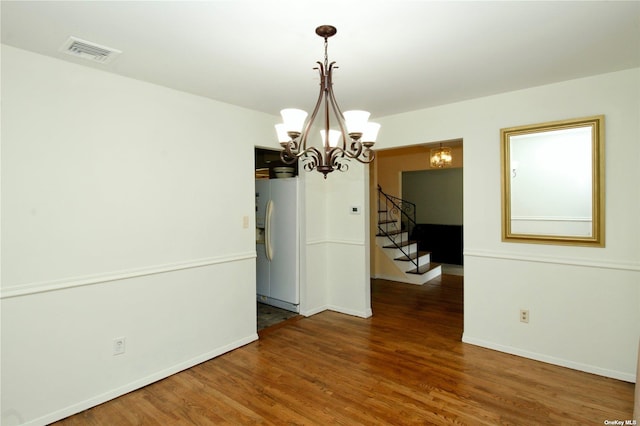 unfurnished dining area with a notable chandelier and dark wood-type flooring