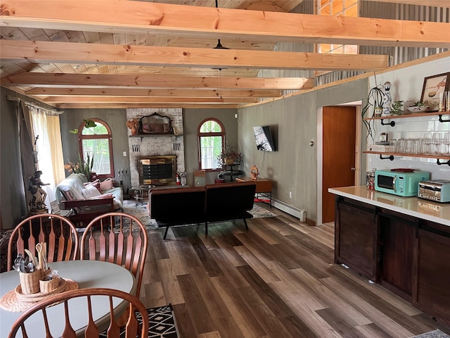 dining space featuring a fireplace, beamed ceiling, wood-type flooring, and plenty of natural light