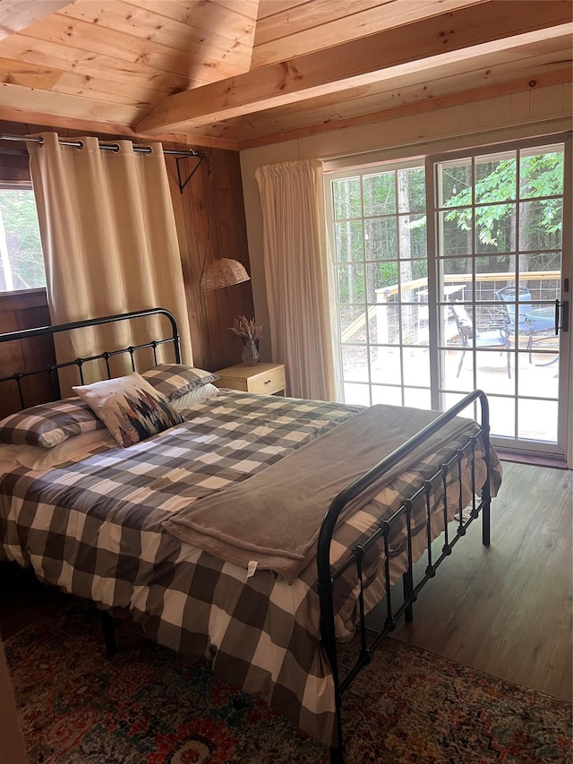 bedroom with lofted ceiling, access to outside, wooden walls, multiple windows, and wood ceiling