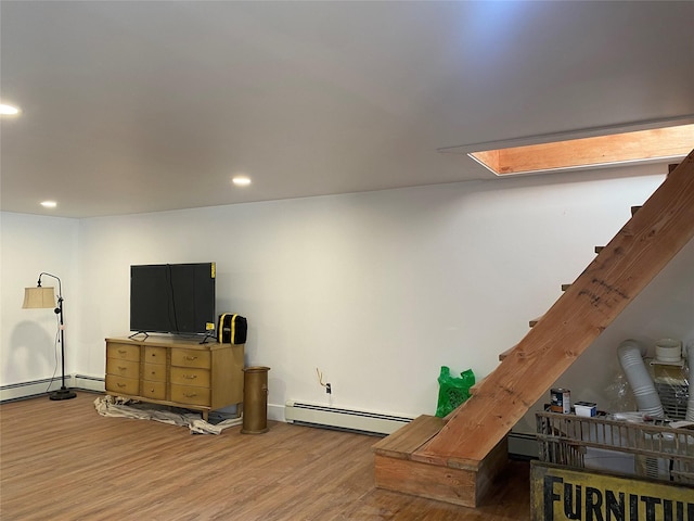 interior space featuring hardwood / wood-style floors, a baseboard radiator, and a skylight