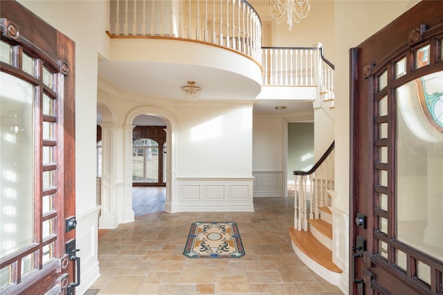 foyer entrance featuring a healthy amount of sunlight, a towering ceiling, and crown molding