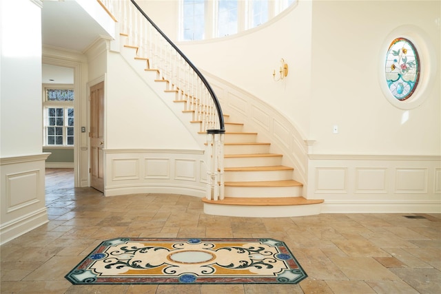 staircase featuring a towering ceiling and crown molding