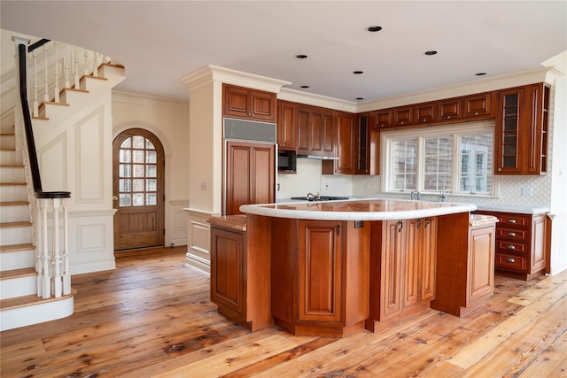 kitchen featuring paneled refrigerator, light hardwood / wood-style floors, a kitchen island, and crown molding