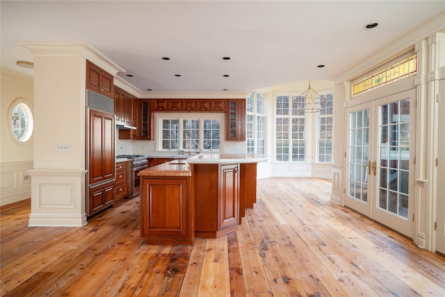 kitchen with stainless steel range, french doors, tasteful backsplash, hardwood / wood-style floors, and a kitchen island