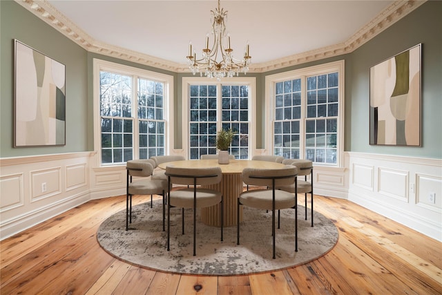 dining area featuring crown molding, light wood-type flooring, and an inviting chandelier