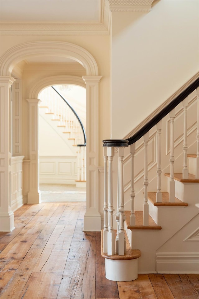 staircase with wood-type flooring and ornamental molding