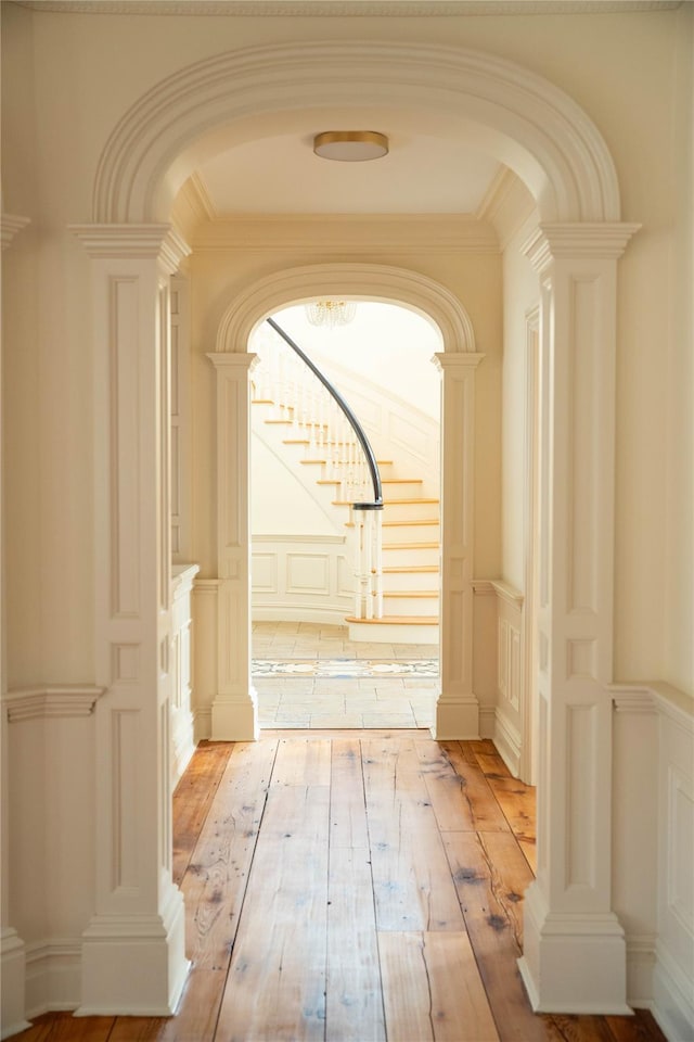 corridor with light hardwood / wood-style flooring and ornamental molding