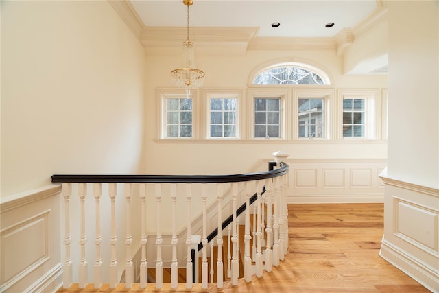 stairs with hardwood / wood-style flooring, ornamental molding, and a chandelier