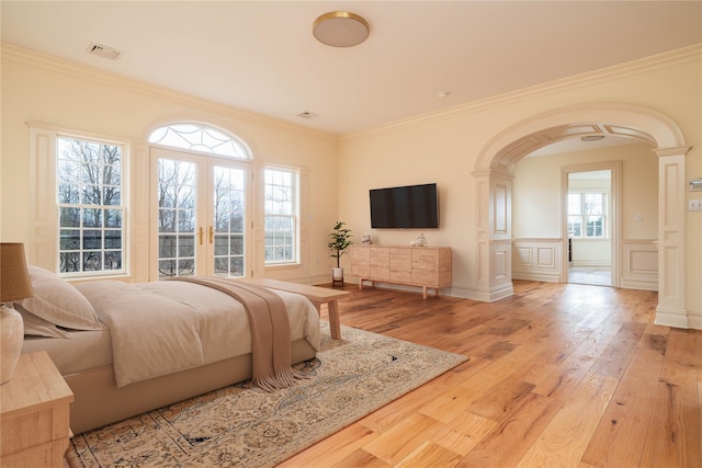 bedroom featuring multiple windows, crown molding, light hardwood / wood-style flooring, and french doors