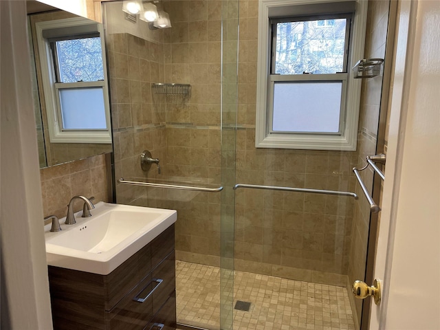 bathroom featuring a shower with door and vanity