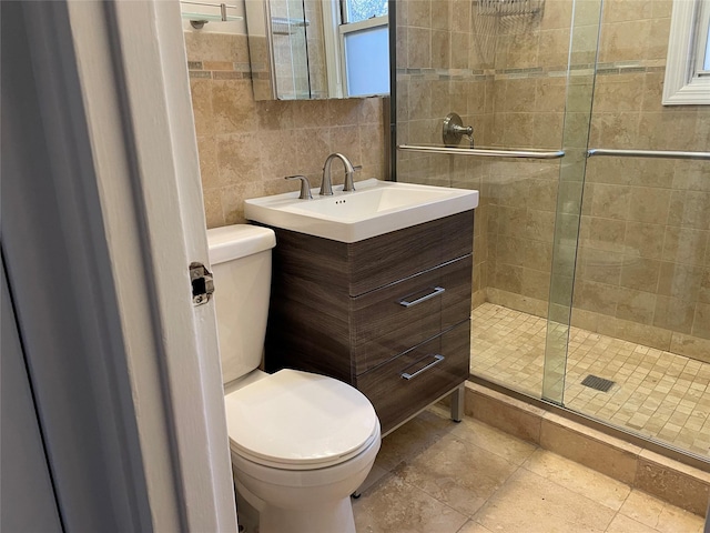 bathroom with tile walls, a shower with door, toilet, and vanity