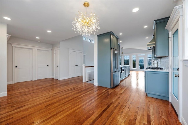 kitchen featuring hardwood / wood-style flooring, decorative light fixtures, a notable chandelier, high quality fridge, and decorative backsplash