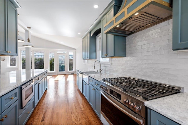 kitchen featuring hardwood / wood-style flooring, hanging light fixtures, stainless steel appliances, custom range hood, and sink