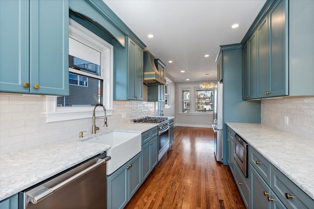 kitchen with dark hardwood / wood-style flooring, decorative light fixtures, sink, custom range hood, and appliances with stainless steel finishes