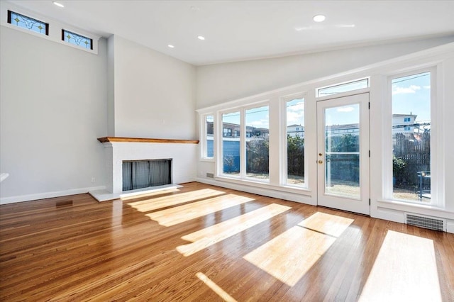 unfurnished living room with light hardwood / wood-style flooring, a brick fireplace, and lofted ceiling