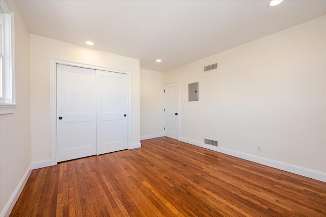 unfurnished bedroom with a closet, hardwood / wood-style flooring, and electric panel