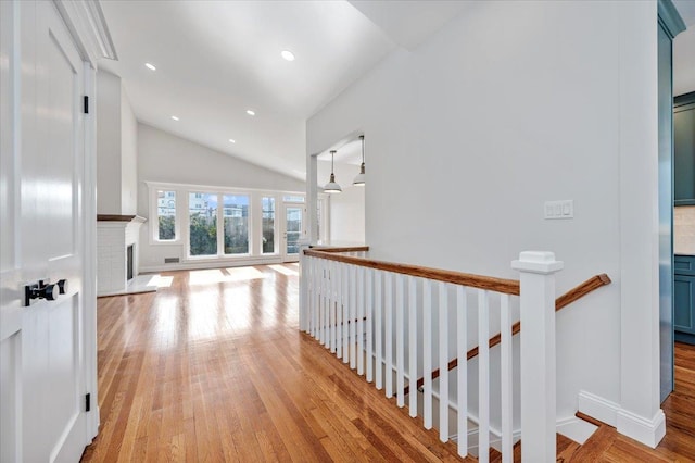 hallway with light wood-type flooring and vaulted ceiling