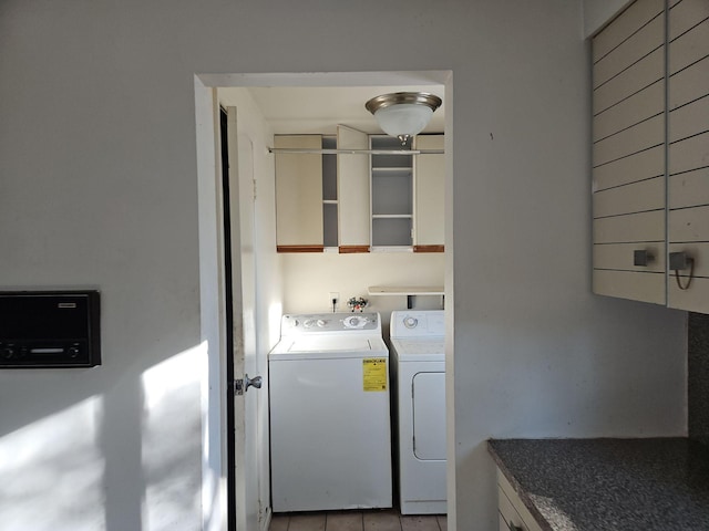 clothes washing area featuring light tile patterned flooring and washer and clothes dryer