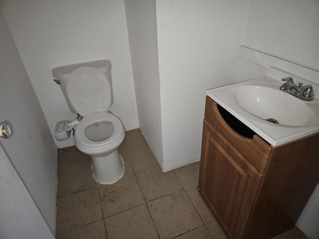 bathroom with toilet, vanity, and tile patterned flooring