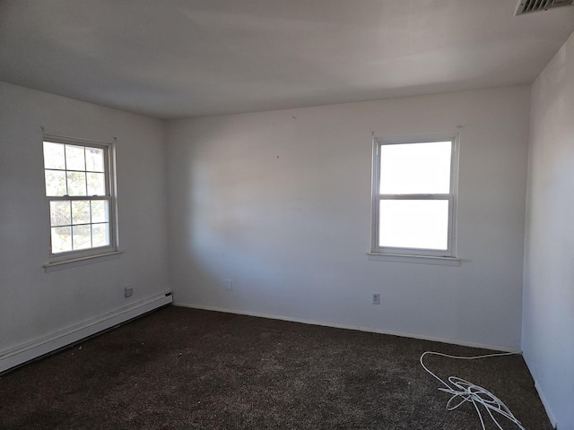 carpeted empty room featuring a baseboard heating unit