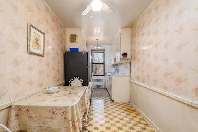 kitchen with stainless steel fridge, radiator, ceiling fan, decorative light fixtures, and white cabinetry