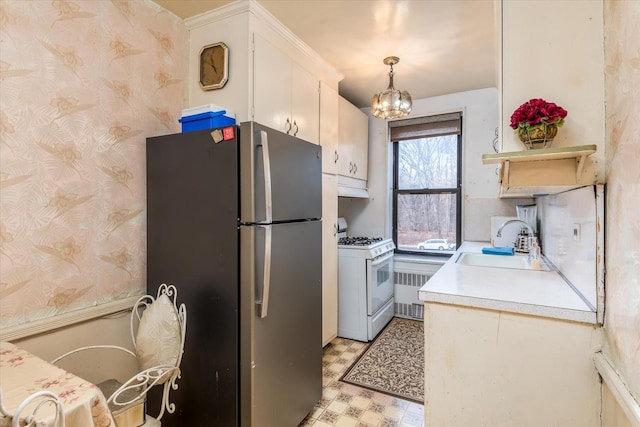 kitchen with stainless steel refrigerator, radiator, sink, hanging light fixtures, and white range with gas cooktop