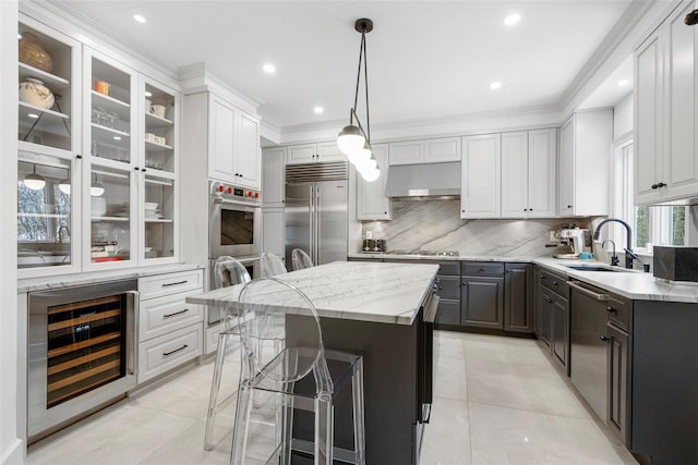 kitchen featuring appliances with stainless steel finishes, white cabinetry, a center island, a kitchen bar, and beverage cooler