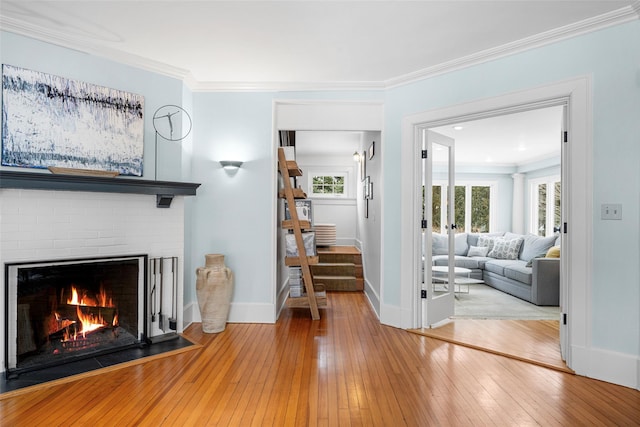 unfurnished living room with crown molding, a brick fireplace, and light wood-type flooring