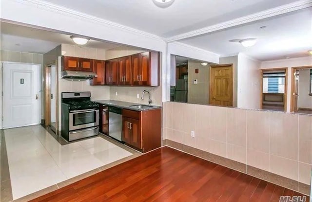 kitchen with ornamental molding, stainless steel appliances, extractor fan, sink, and tile walls