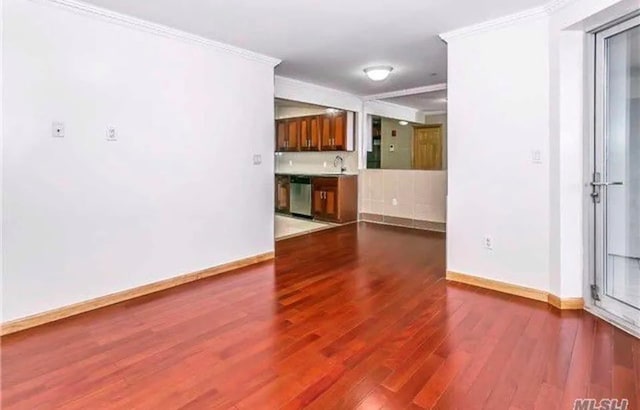 empty room with wood-type flooring, crown molding, and sink