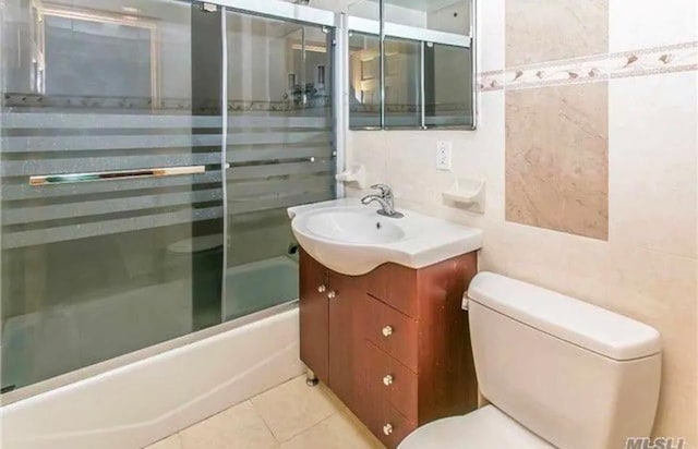 full bathroom featuring tile patterned flooring, vanity, toilet, and bath / shower combo with glass door