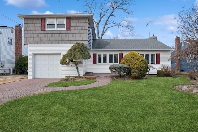 view of front of house with a front lawn, central AC unit, and a garage