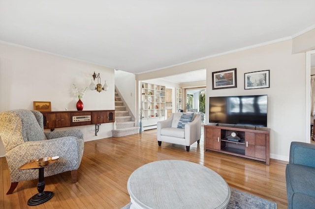 living room featuring a baseboard heating unit, crown molding, and wood-type flooring