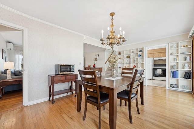 dining room with light wood-type flooring, crown molding, a wall unit AC, and a notable chandelier