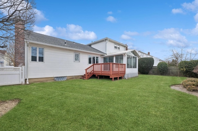 rear view of house featuring a deck, a yard, and a sunroom