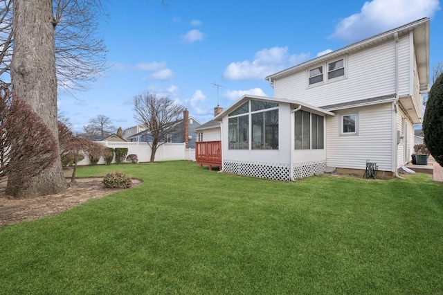 back of house with a wooden deck, a sunroom, and a lawn