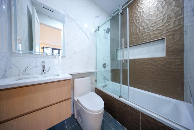 full bathroom with combined bath / shower with glass door, vanity, tile patterned flooring, and toilet