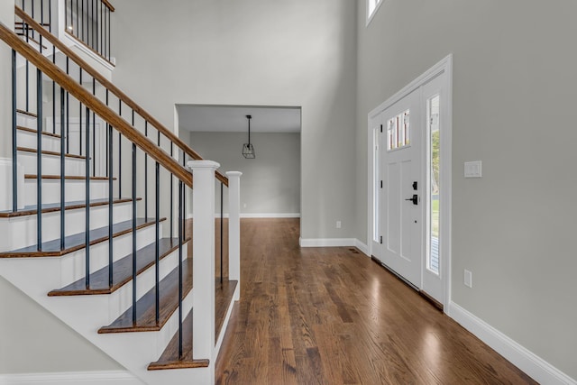 entrance foyer featuring a towering ceiling and dark hardwood / wood-style flooring