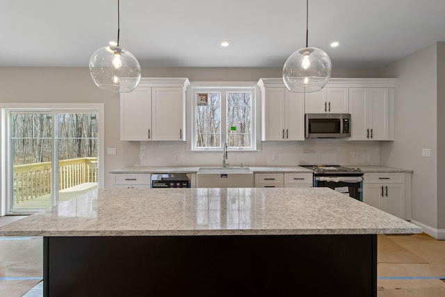 kitchen with decorative light fixtures, white cabinetry, sink, and appliances with stainless steel finishes