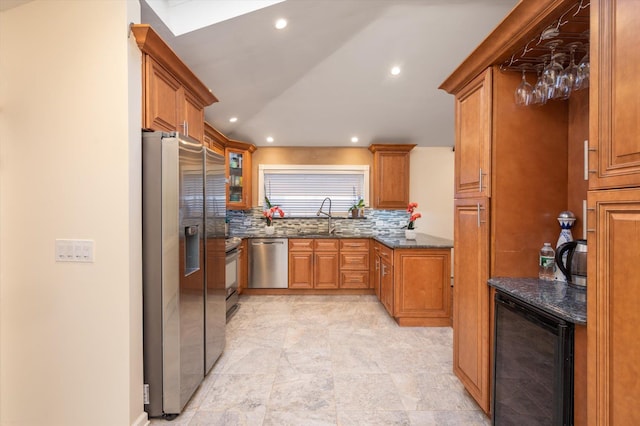 kitchen with decorative backsplash, wine cooler, dark stone counters, appliances with stainless steel finishes, and sink