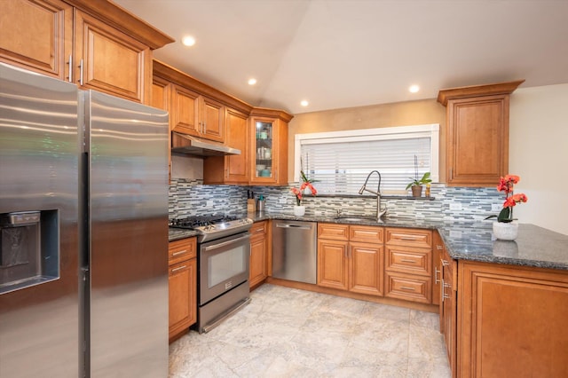 kitchen with stainless steel appliances, sink, tasteful backsplash, kitchen peninsula, and dark stone counters