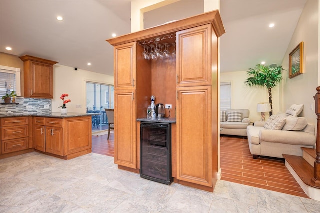 kitchen featuring dark stone countertops, decorative backsplash, and wine cooler