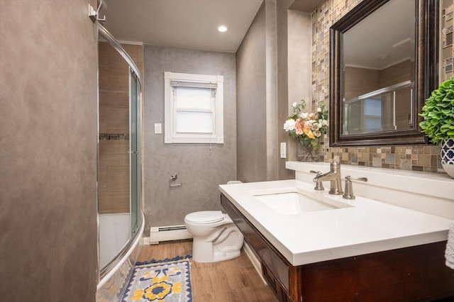 bathroom featuring baseboard heating, toilet, wood-type flooring, walk in shower, and vanity