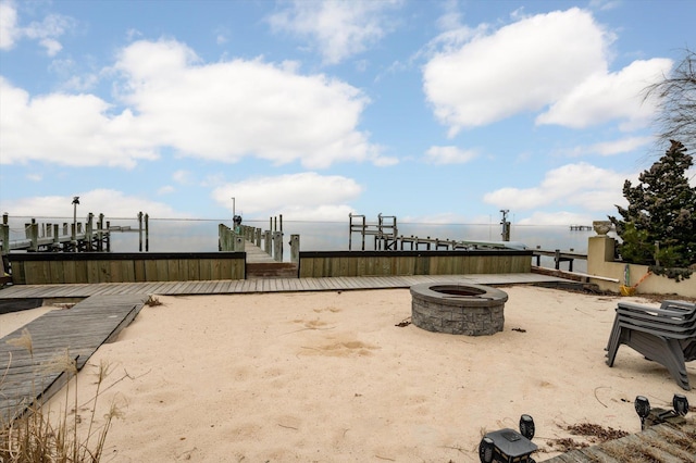 view of yard featuring a boat dock, a water view, and an outdoor fire pit