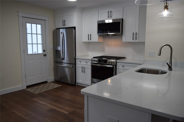 kitchen with dark wood-style flooring, stainless steel appliances, backsplash, a sink, and light stone countertops