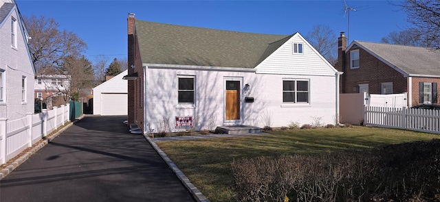 view of front of home featuring a garage, brick siding, an outdoor structure, fence, and a front lawn